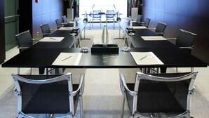 Un salón de conferencias con una larga mesa, sillas y un amplio ventanal.