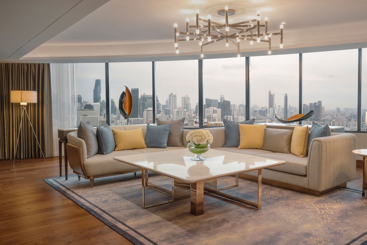 A modern living room with a large window, a sofa set, a coffee table, and a city view.