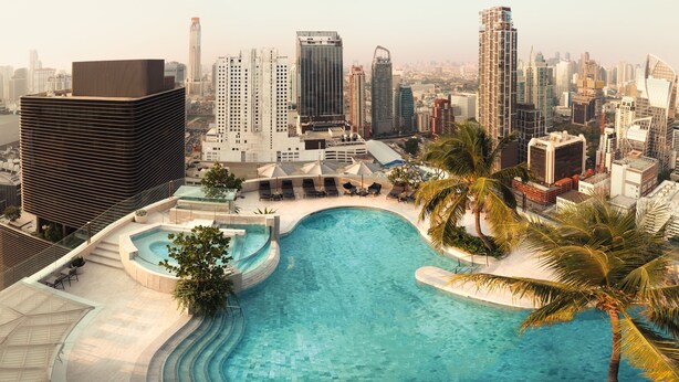 A rooftop pool with a cityscape view, surrounded by palm trees and modern buildings. - InterContinental Bangkok by IHG (Bangkok)