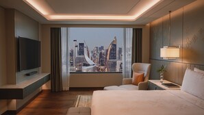 A modern hotel room with a large bed, a TV, a city view, and a cityscape visible through the window. - InterContinental Bangkok by IHG (Bangkok)
