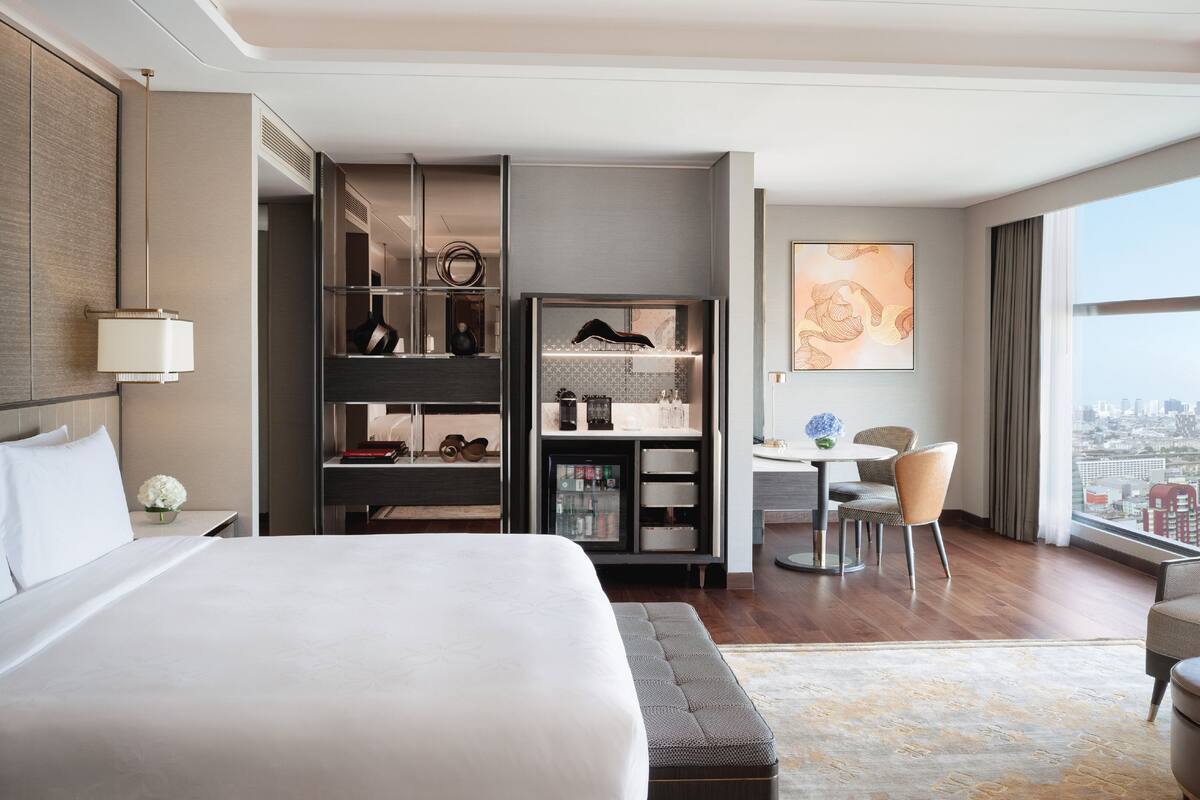 A hotel room with a large bed, a desk, and a view of the city.
