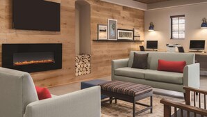 A modern living room with a fireplace, a flat-screen TV mounted on the wall, and a comfortable seating area with a sofa and chairs.
