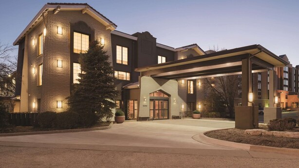 A multi-story hotel with a covered entrance and a landscaped driveway.