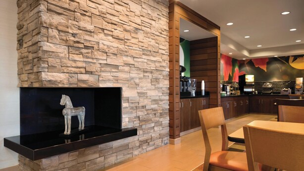 Une cuisine moderne avec un mur d’accent en pierre, un comptoir noir et un coin repas en bois avec des chaises.