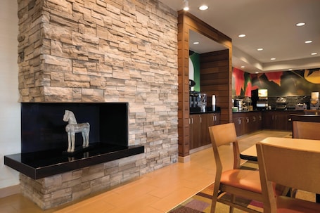 A modern kitchen with a stone accent wall, a black countertop, and a wooden dining area with chairs.