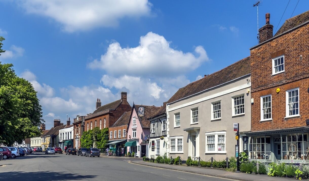 A street lined with traditional buildings, including a pub with a signboard and a shop with a green awning.