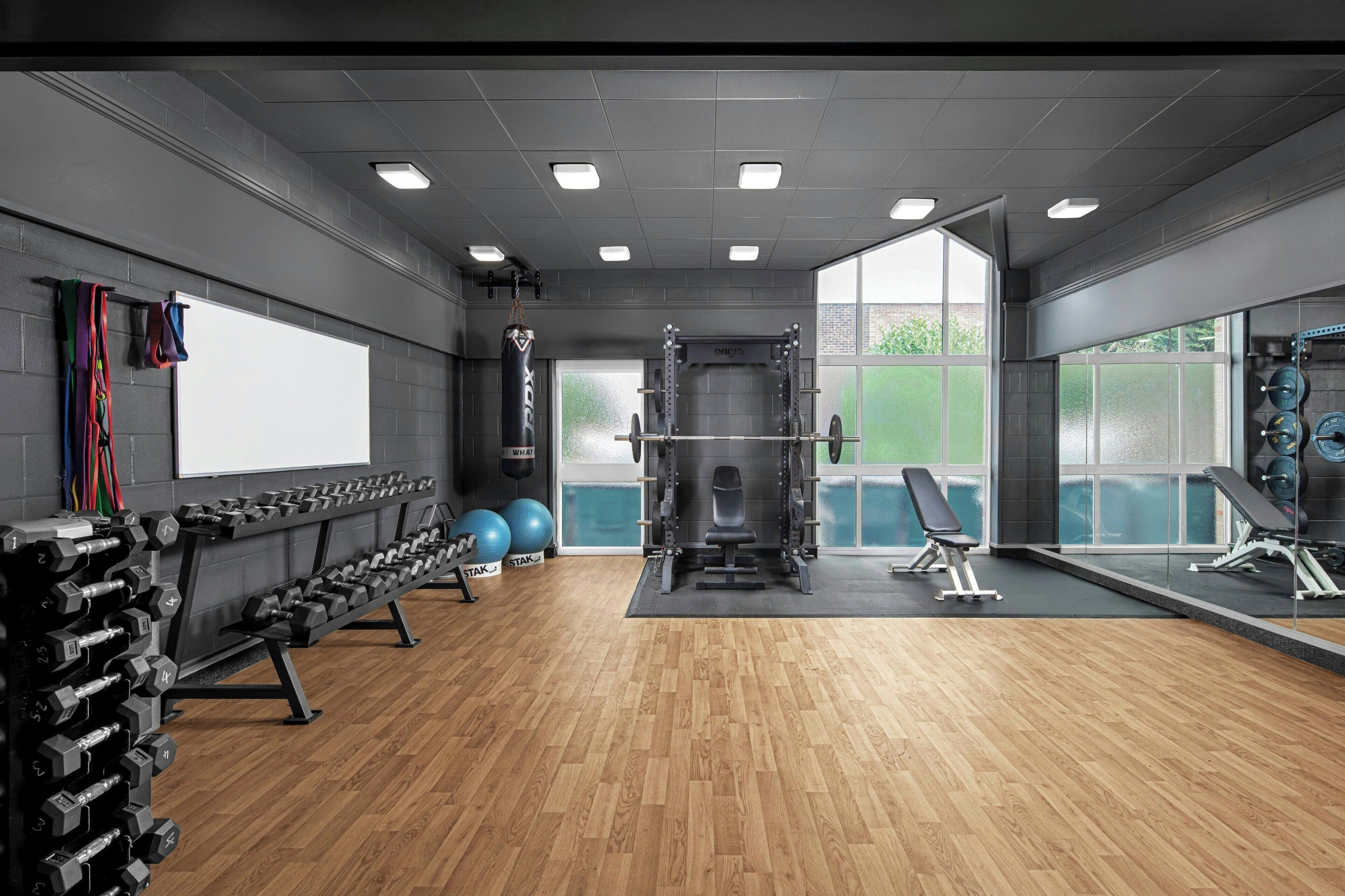 Une salle de sport équipée de matériel de musculation, de ballons d’exercice et d’un banc.