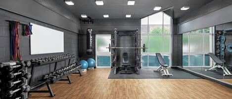 Une salle de sport équipée de matériel de musculation, de ballons d’exercice et d’un banc.