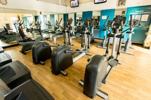 A gym with various exercise machines, a wooden floor, and a blue wall with a sign. - Delta Hotels by Marriott Colchester (Colchester)