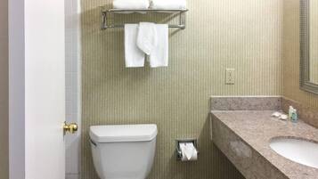 A bathroom with a toilet, a towel rack with towels, a sink, and a mirror.