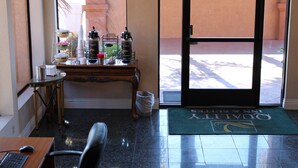 Uma área de recepção de hotel com balcão, lixeira, porta e tapete.