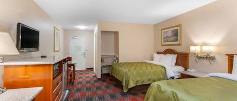 Una habitación de hotel con cama, mesita de noche, lámpara y televisor sobre un escritorio.