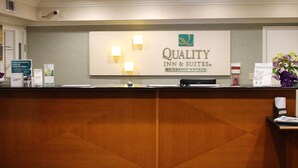 Um balcão de recepção com uma placa indicando "Quality Inn & Suites by Choice Hotels".