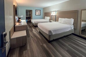 A hotel room with two beds, a desk with a lamp, a mirror, and a wooden floor. - Quality Inn Cairo (Cairo)