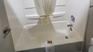Uma banheira, uma toalha, um cortinado de chuveiro e um vaso sanitário.