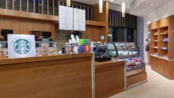 A Starbucks counter with a menu board, a coffee machine, and a display case with beverages.