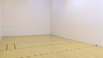 A squash court with a wooden floor and white walls.