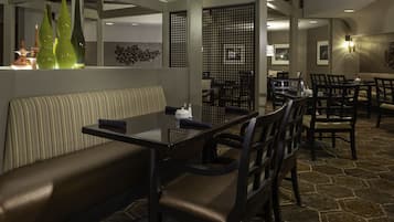Un interior de restaurante con una zona de cabinas, una larga mesa de comedor y sillas.