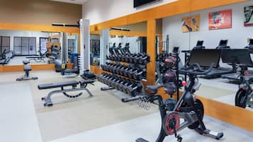 A gym with exercise equipment, mirrors, and a wall-mounted TV.