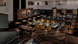 A modern lounge area with a bar, seating arrangements, and a staircase leading to an upper level.