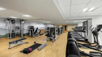 Une salle de sport équipée de tapis de course, de vélos elliptiques et de matériel de musculation.