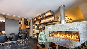 A modern interior with a stone fireplace, black chairs, and a wooden table.