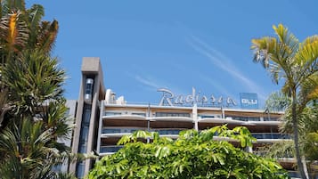 Un hotel de diseño moderno, con varios balcones y un letrero llamativo.