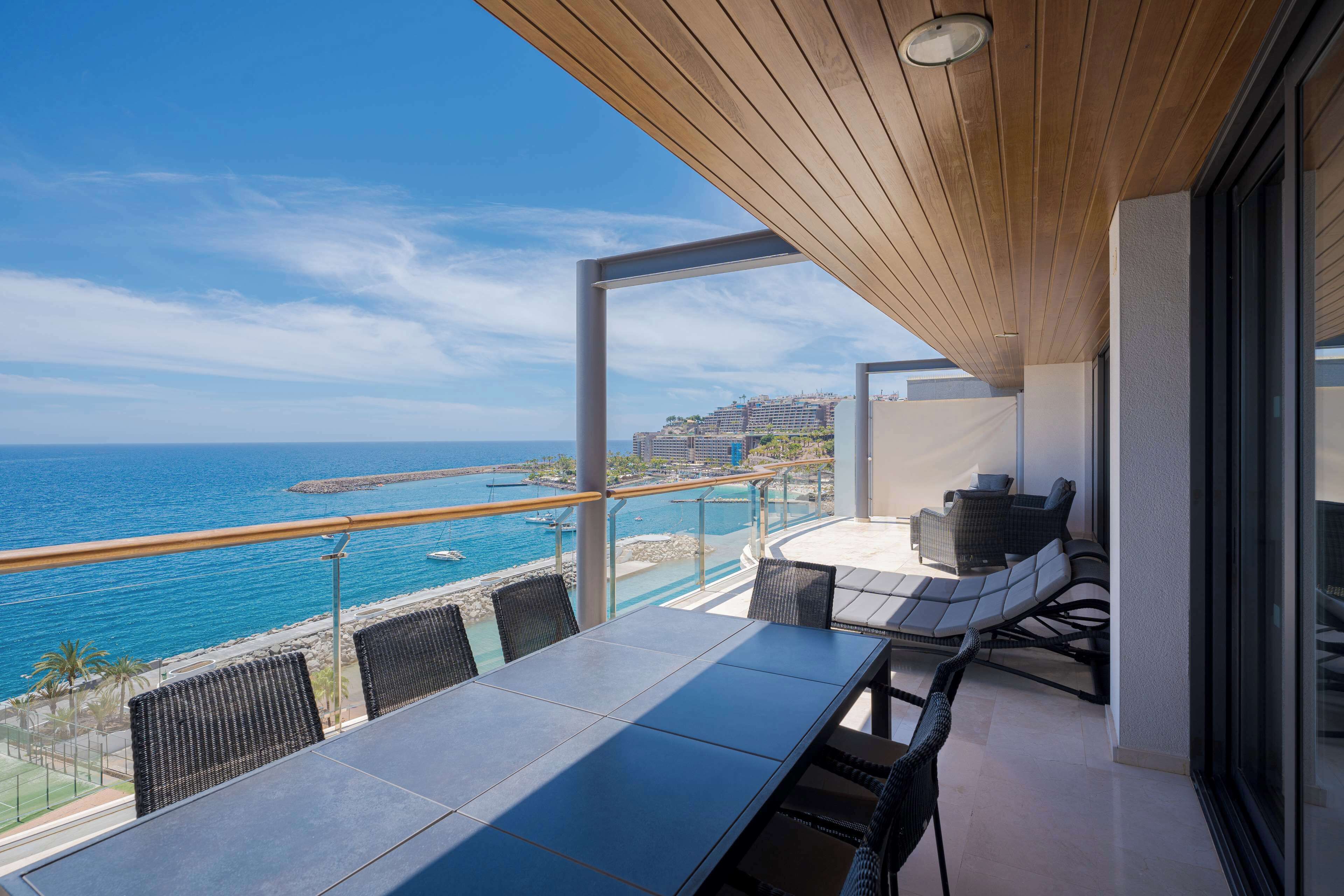 Un balcón con vista al océano y al paisaje urbano.