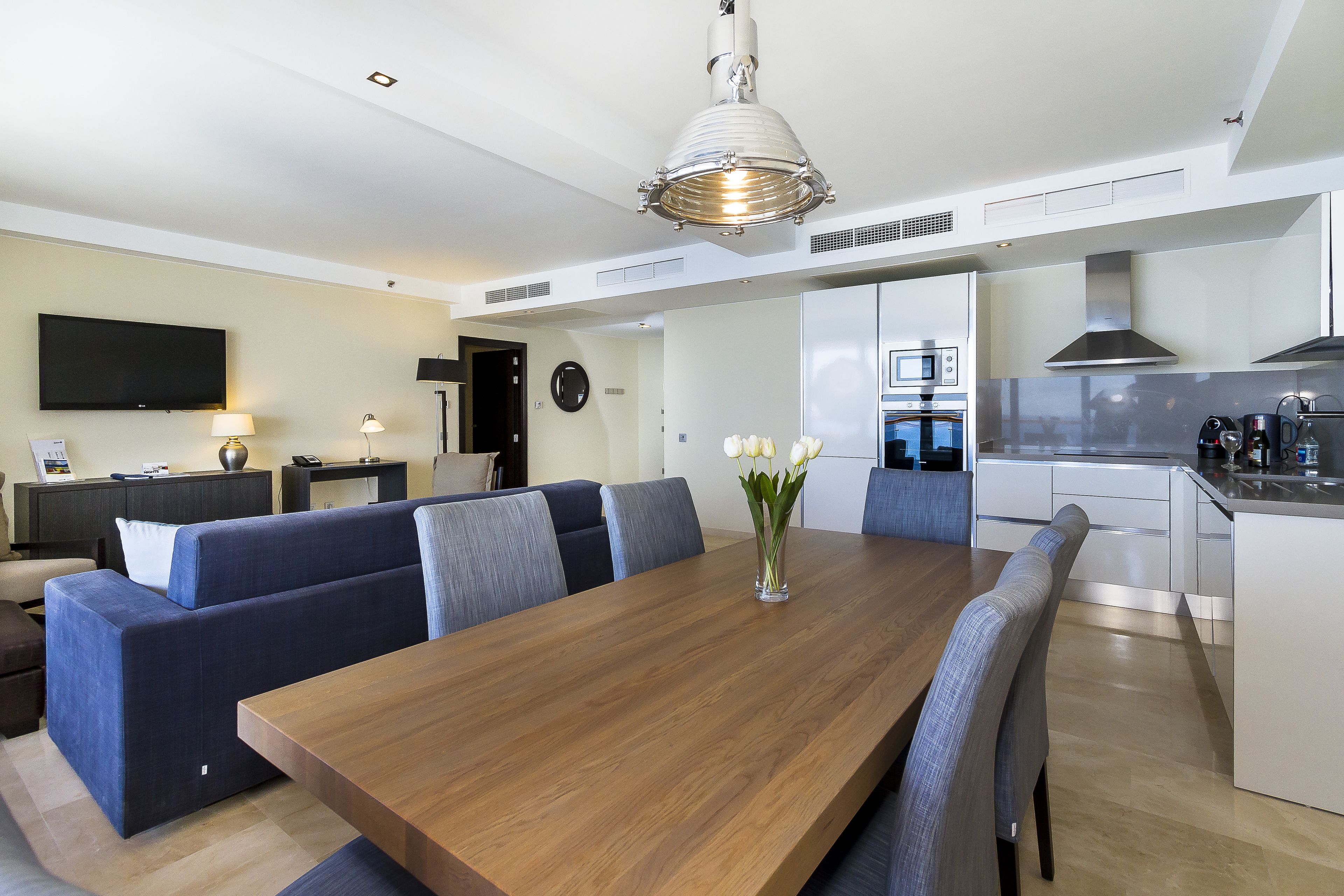 Una cocina moderna con una mesa de comedor de madera, un horno empotrado y un microondas.