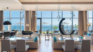 Un comedor moderno con amplia vista al océano, una escultura circular singular y una disposición de asientos acogedora.