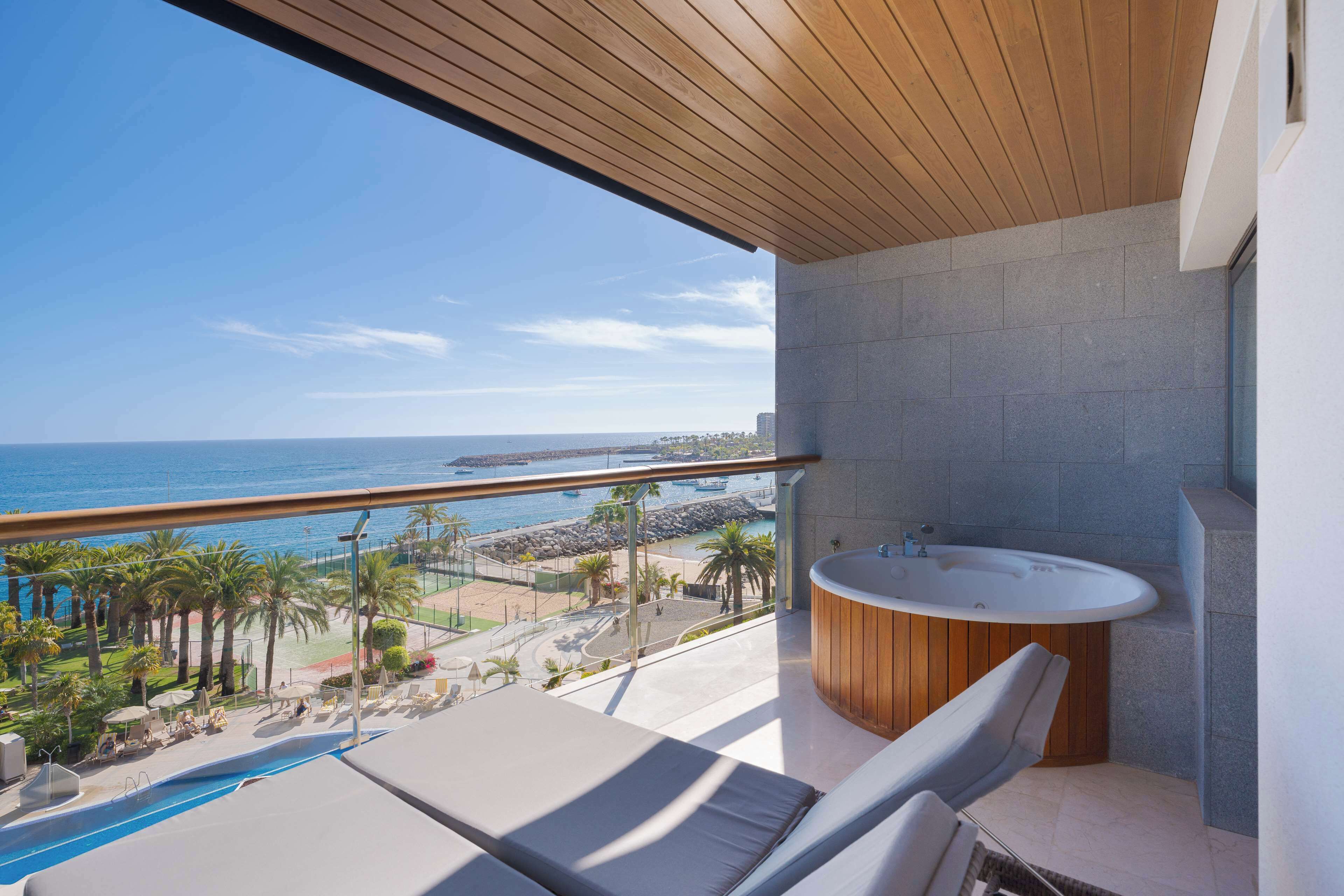 Un balcón con vistas al mar, un jacuzzi y una piscina.