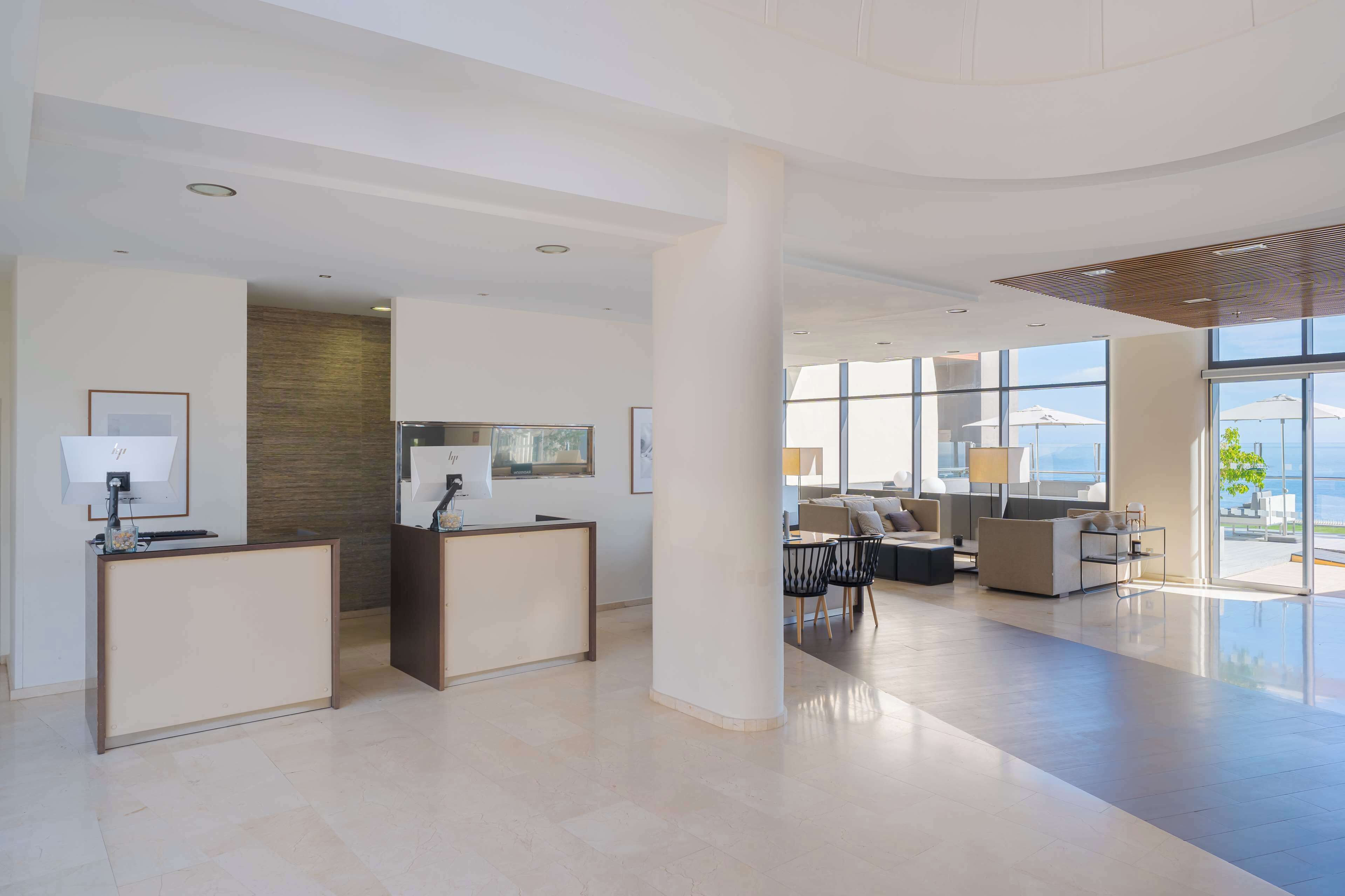 Eine großzügige Lobby mit Empfangsbereich, Sitzgelegenheiten und großen Fenstern mit Blick ins Freie.