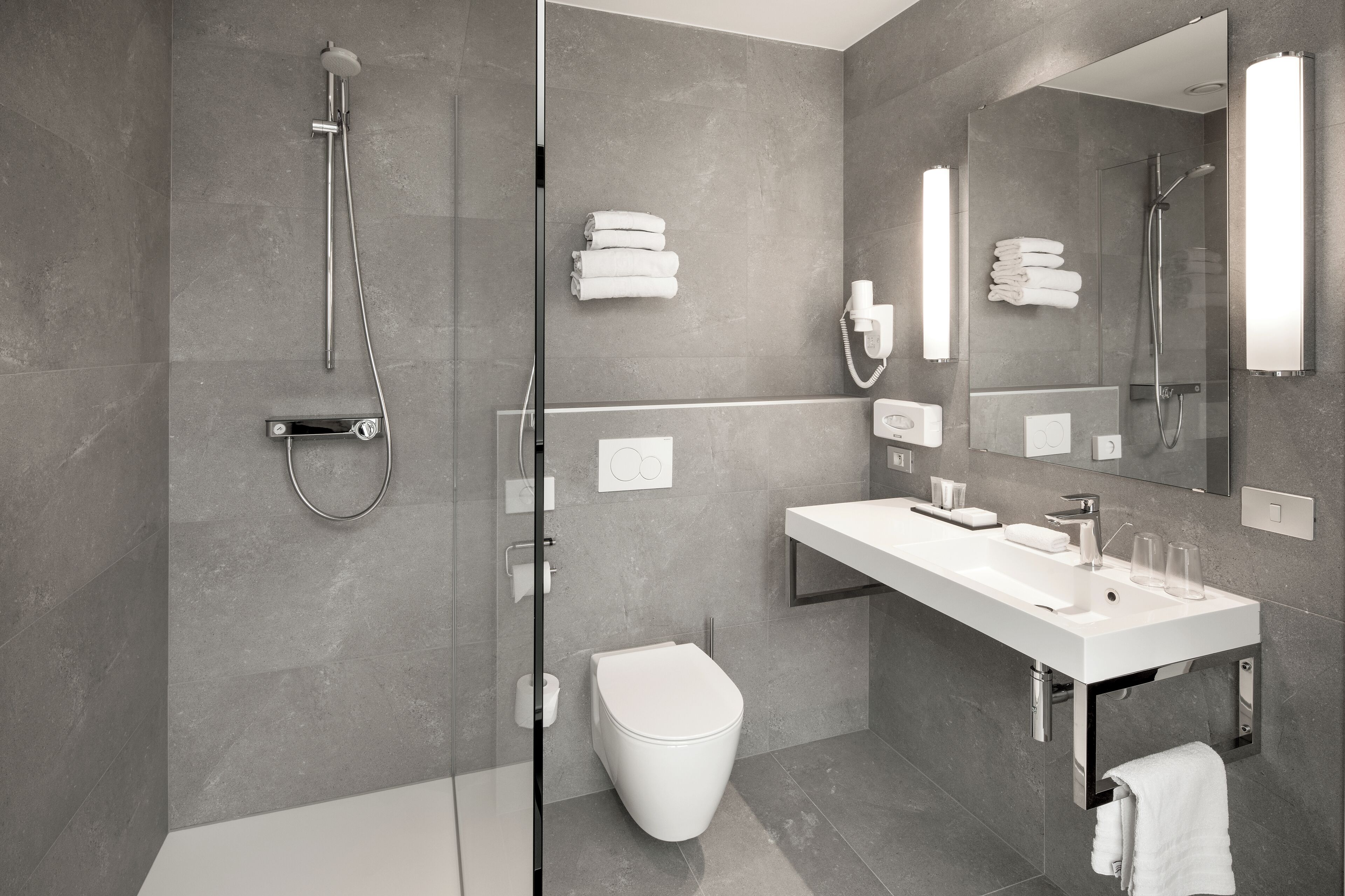 A modern bathroom with a glass-enclosed shower, a white sink, and a toilet.