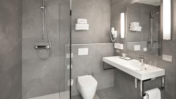 A modern bathroom with a glass-enclosed shower, a white sink, and a toilet.