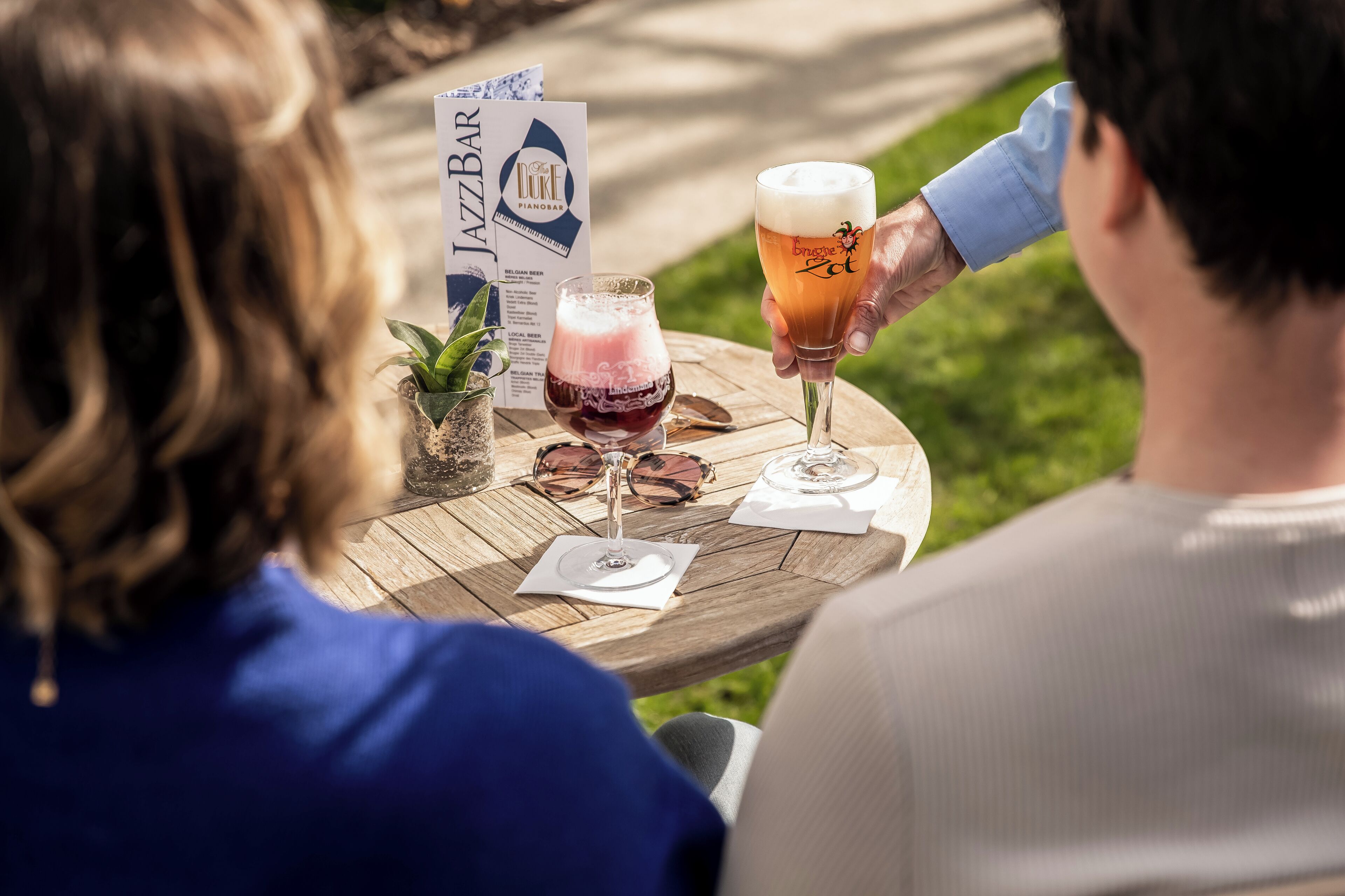 Une table en bois, un menu, deux verres de bière et une bouteille de vin.