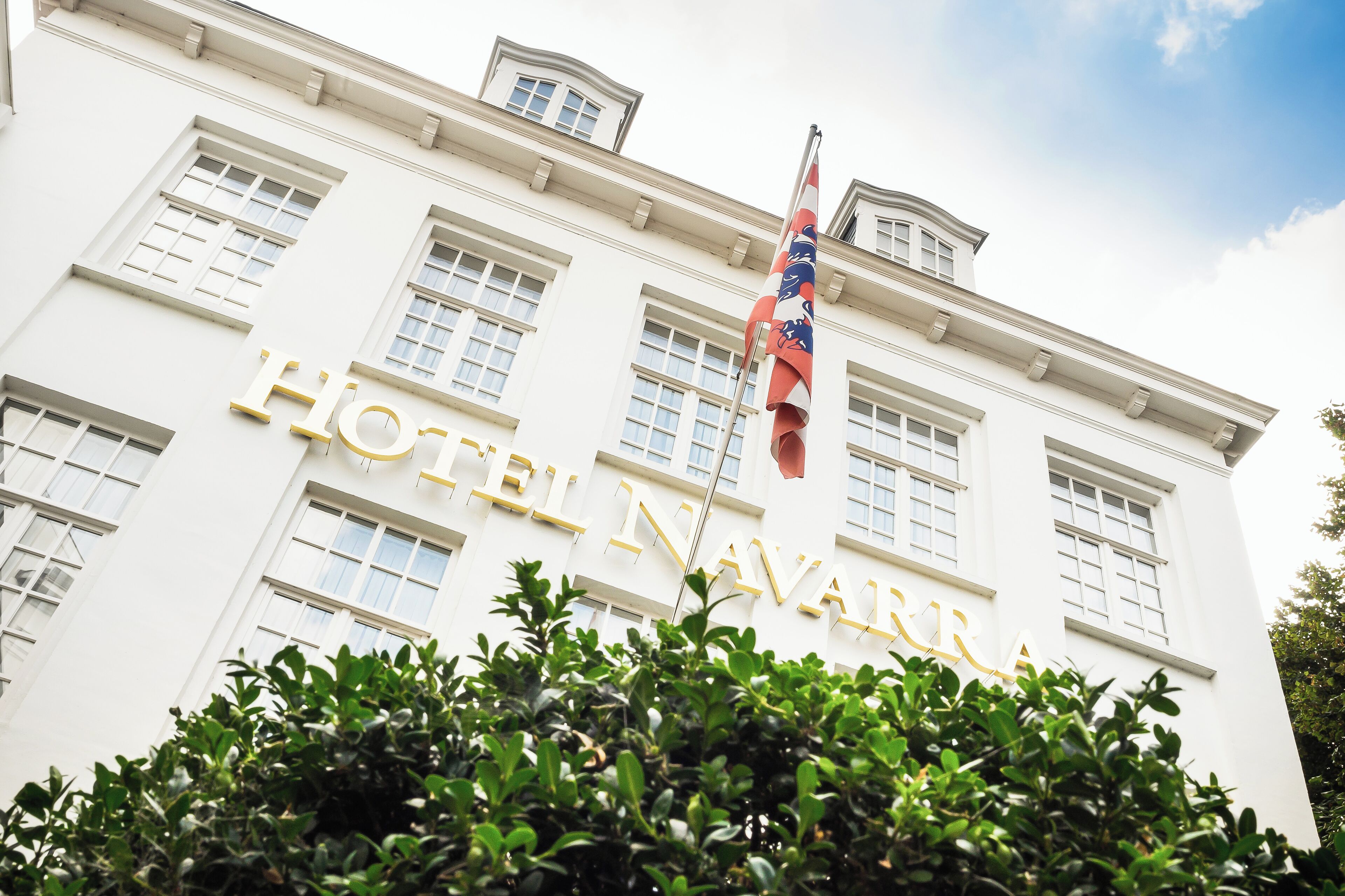 A white building with the sign "HOTEL NAVARRA" in gold letters.