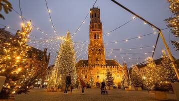 A historic building with a prominent tower, surrounded by Christmas trees and string lights.
