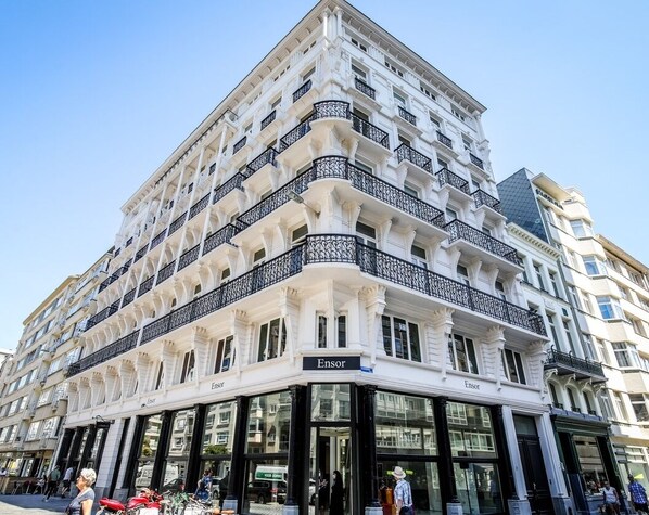 Un edificio en esquina con varios balcones y un escaparate que dice 'Ensor'.