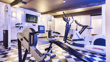 A gym with various exercise equipment, a television, and a checkered floor.