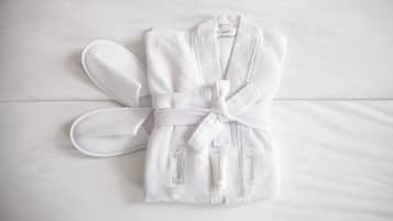A white bathrobe and slippers on a bed.