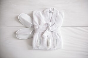 Una bata blanca y zapatillas sobre la cama.