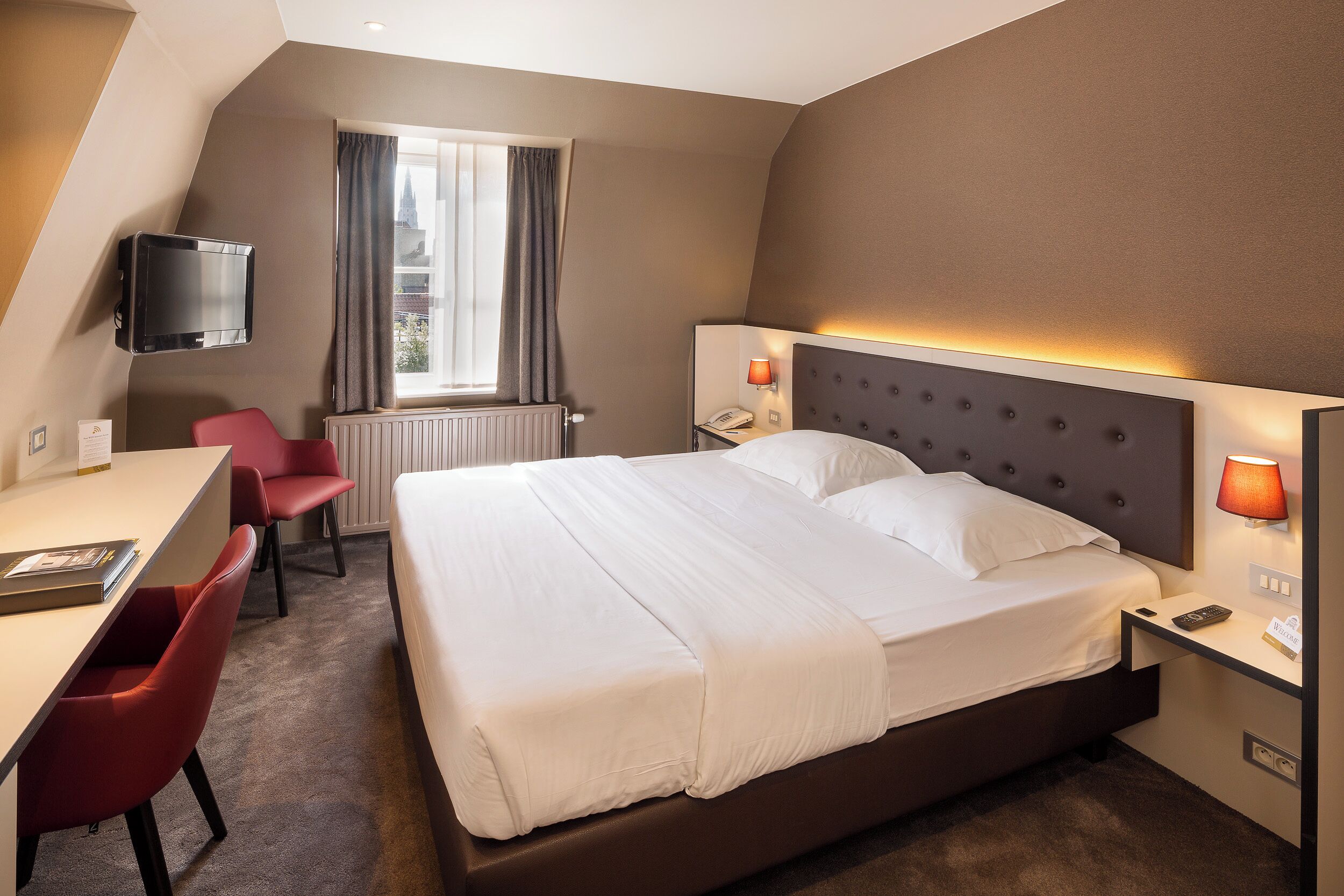 A hotel room with a bed, desk, and chair.