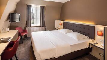 A hotel room with a bed, desk, and chair.