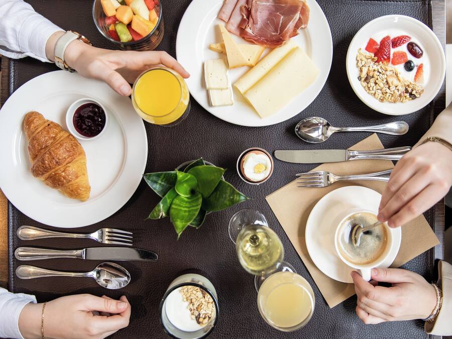 Een ontbijttafel met borden eten, een croissant en een glas sap.
