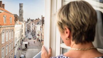 A view from a window overlooking a street with buildings and a tower.