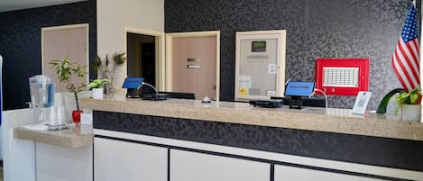 A reception desk with a computer, a 'WELCOME!' sign, an American flag, and a door with a 'WELCOME' sign.