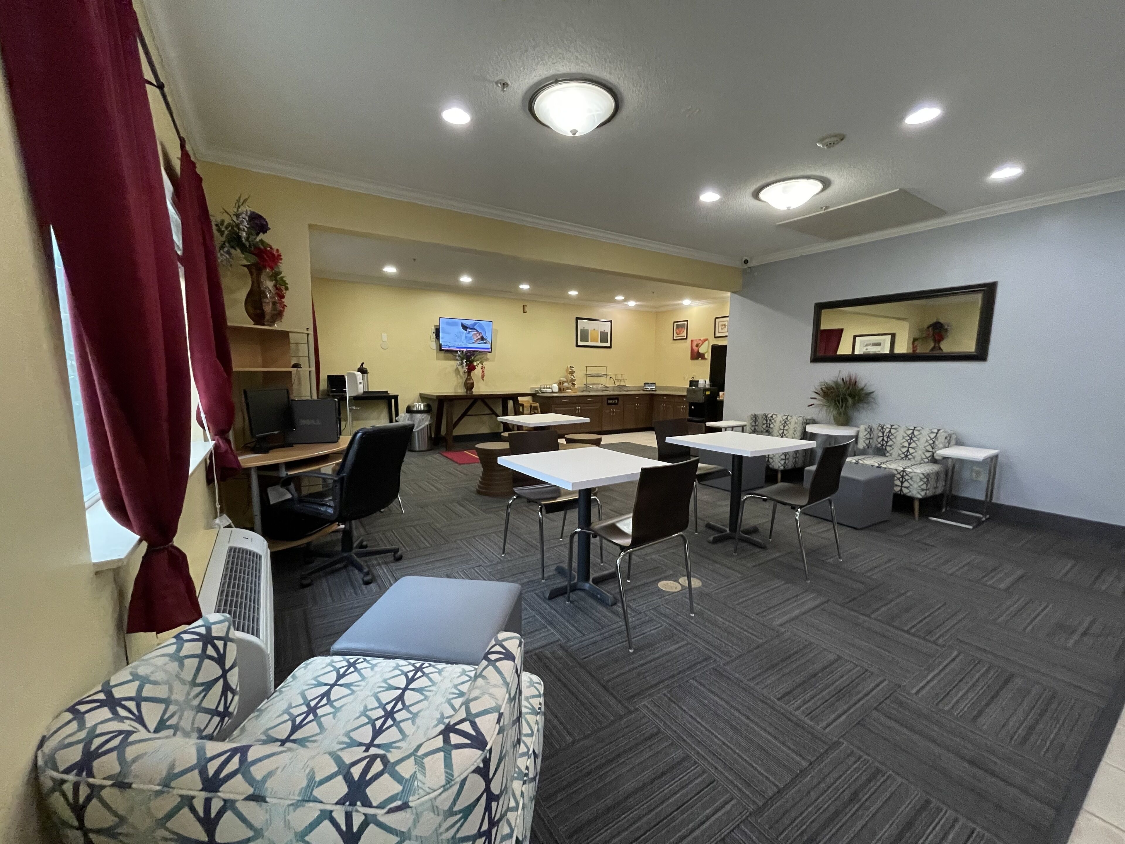 A hotel room with a dining area, a TV, and a mirror on the wall.
