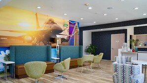 Vestíbulo de hotel con mostrador de recepción, zona de estar y un gran mural.