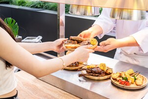 A buffet with various grilled meats, vegetables, and corn on the cob.
