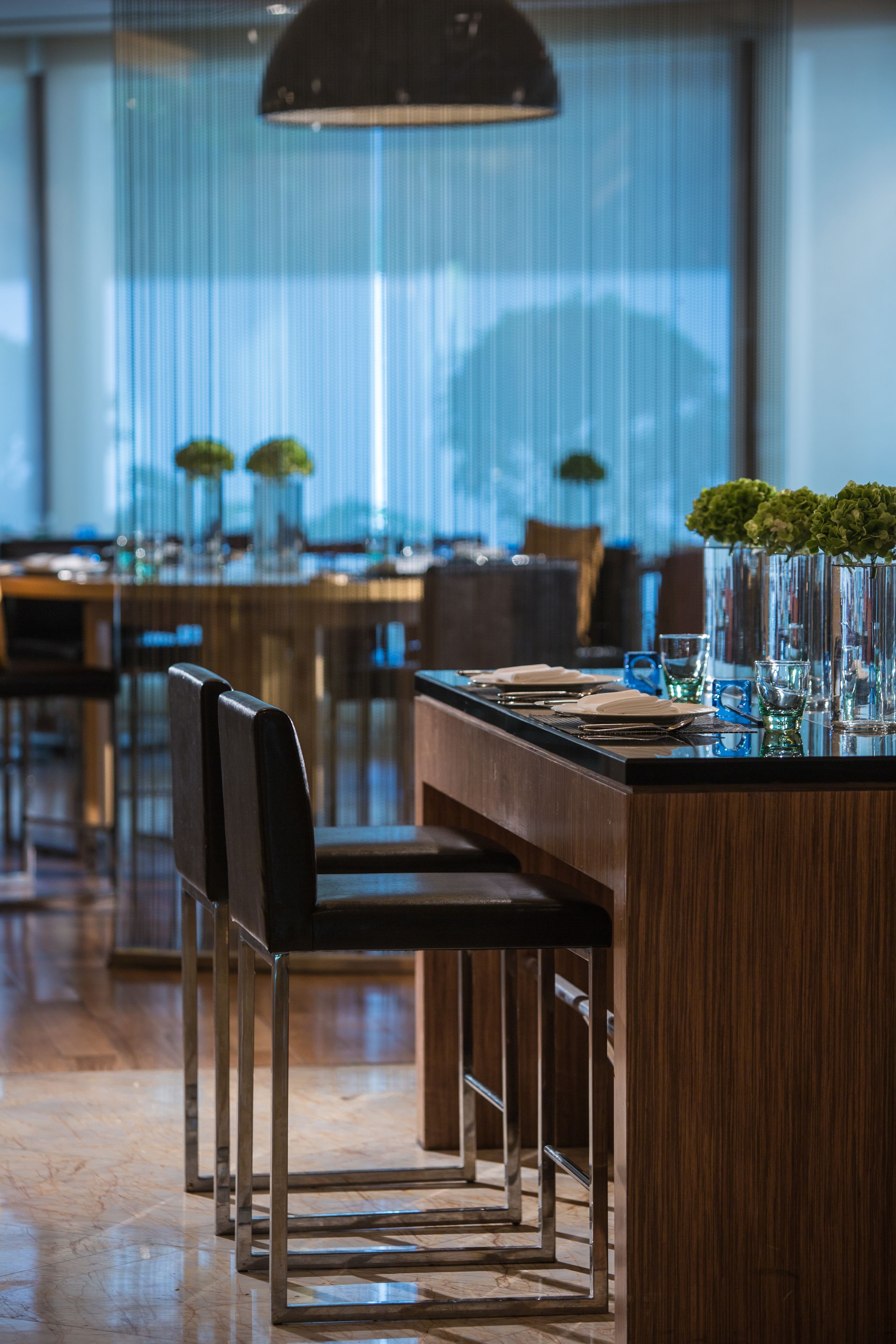 Un espace de restauration moderne avec des tables et des chaises en bois, ainsi que de grands vases ornés de plantes vertes.